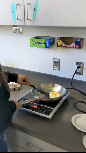 A Culinary Student cooks a sunny side up egg as one of the labs.