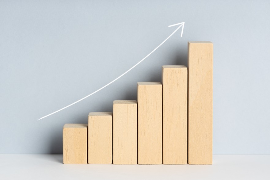 Wooden block financial bar chart graph with upward trend line drawn on background. Growing business concept